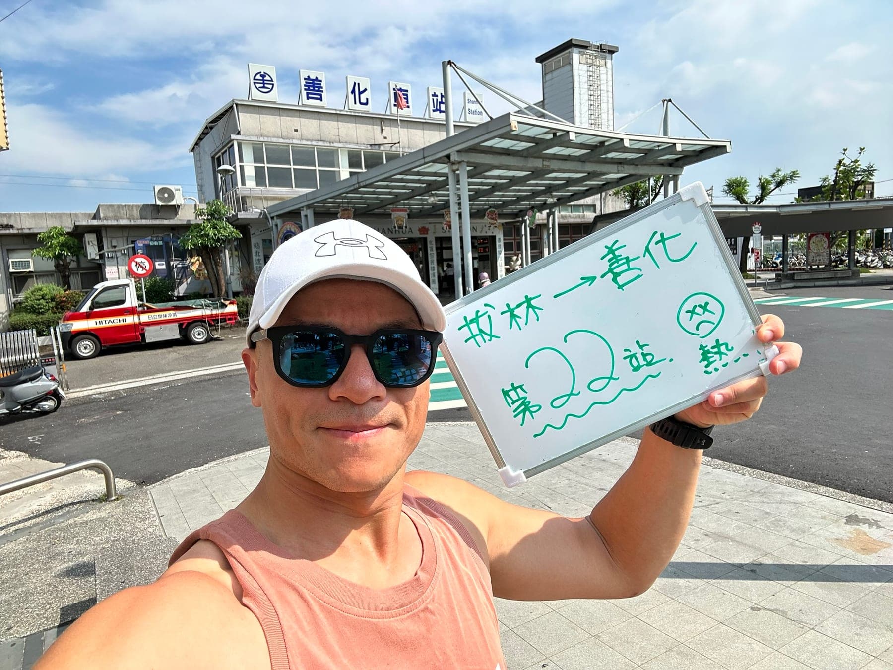 站主在善化站站牌前的走訪紀錄照，手持寫著「徒步環島 第 22 站　拔林 → 善化」的白板