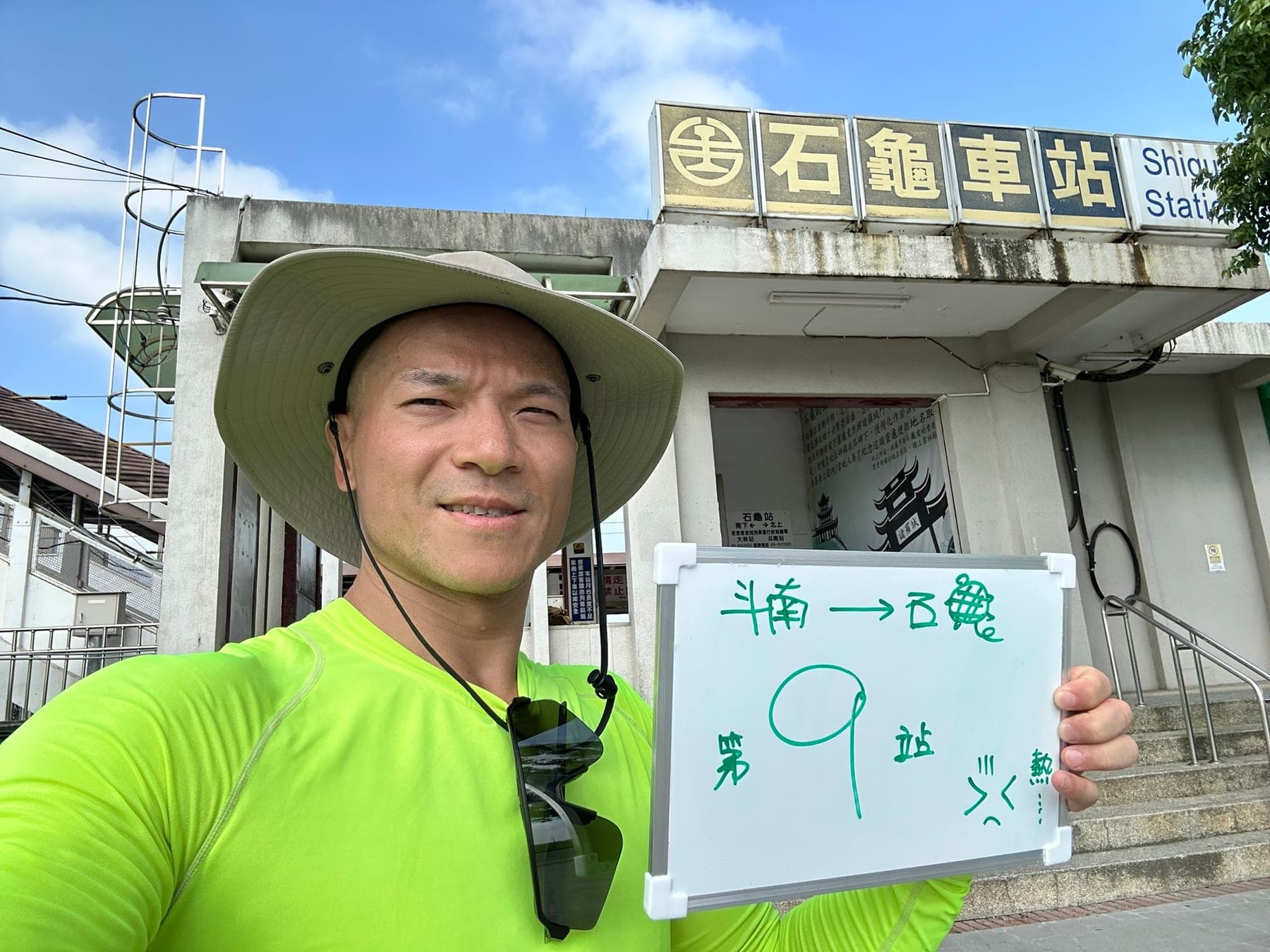 站主在石龜站站牌前的走訪紀錄照，手持寫著「徒步環島 第 9 站　斗南 → 石龜」的白板