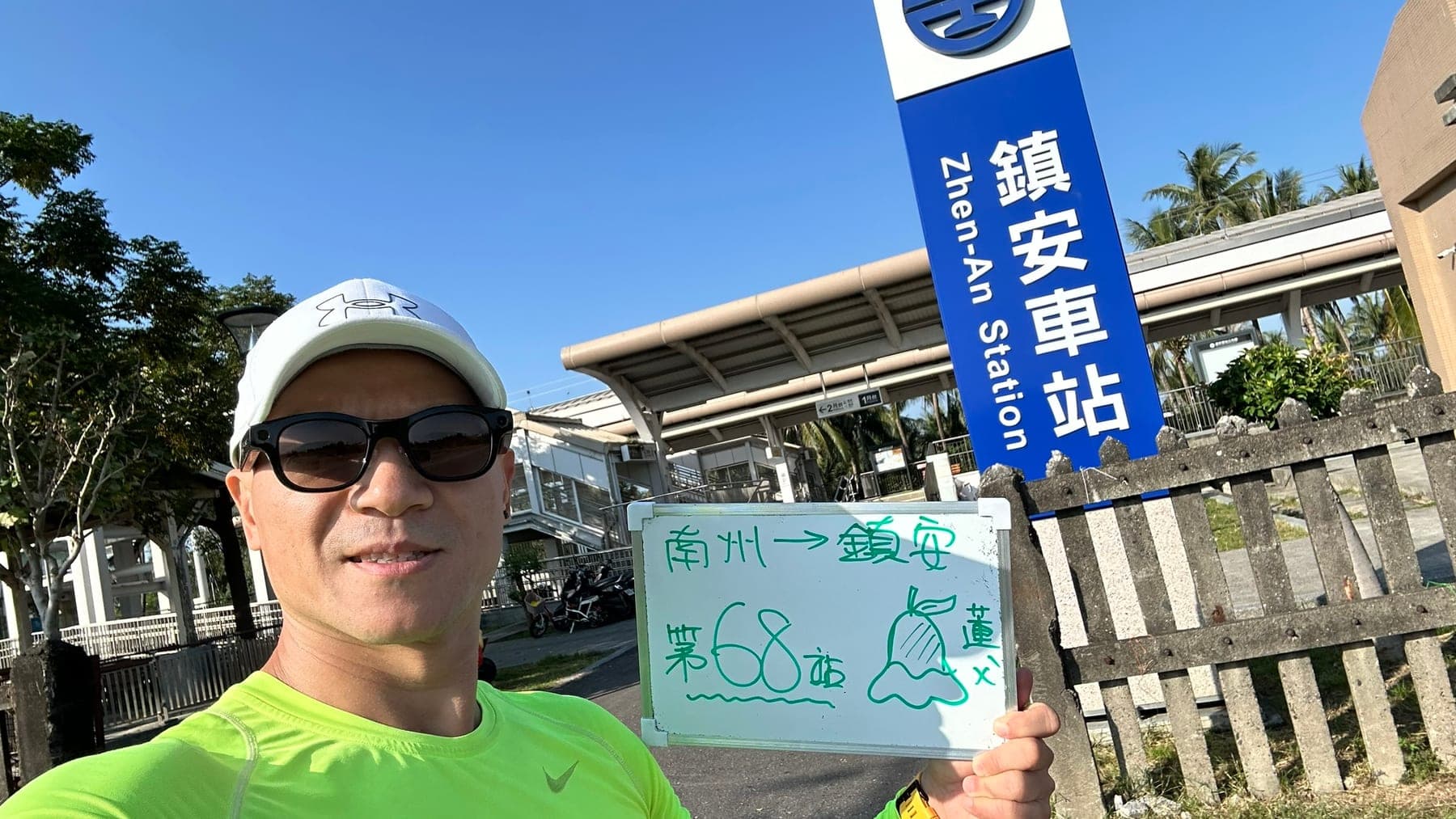 站主在鎮安站站牌前的走訪紀錄照，手持寫著「徒步環島 第 68 站　南州 → 鎮安」的白板
