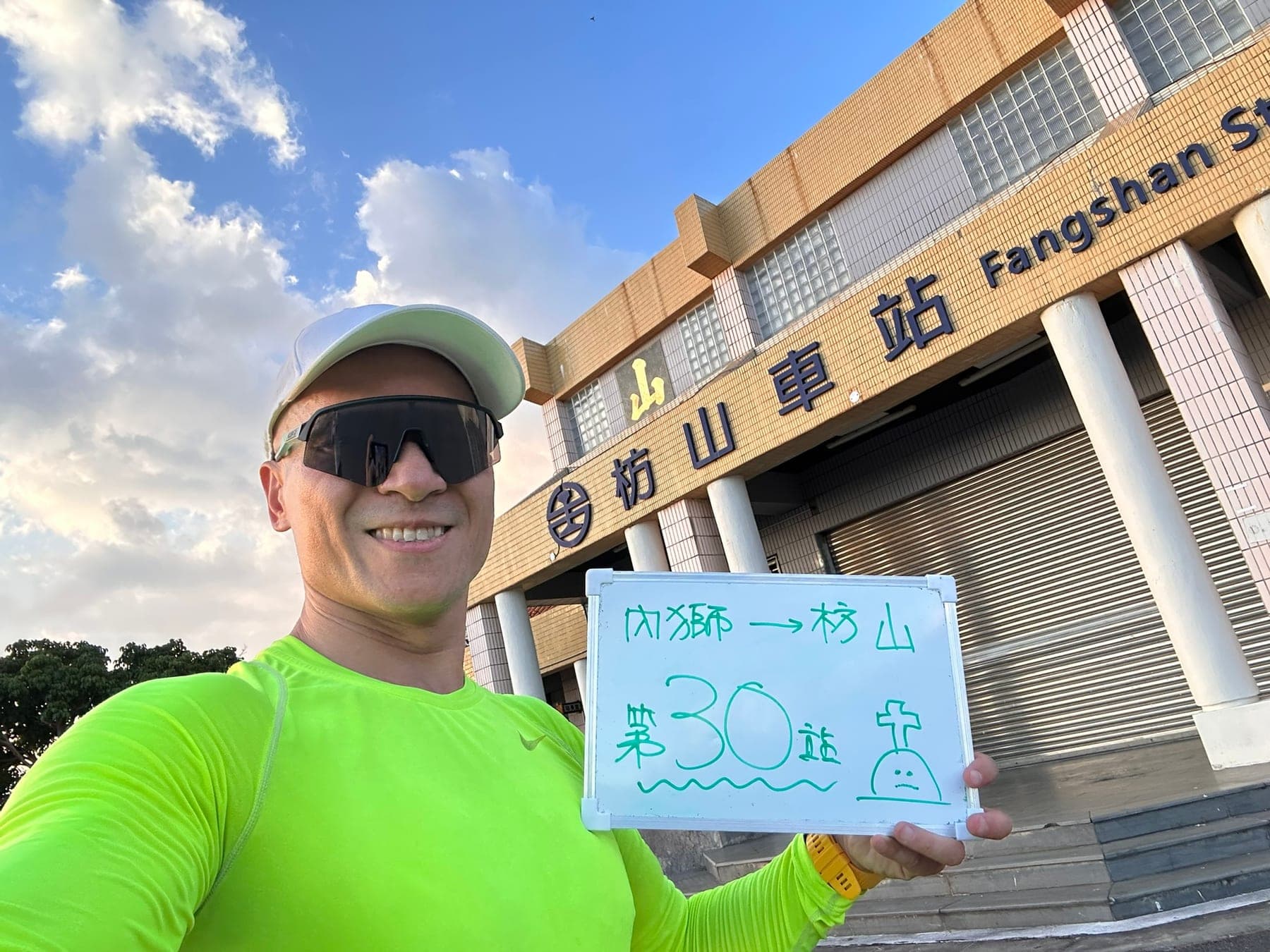 站主在枋山站站牌前的走訪紀錄照,手持寫著「徒步環島 第 30 站 內獅 → 枋山」的白板