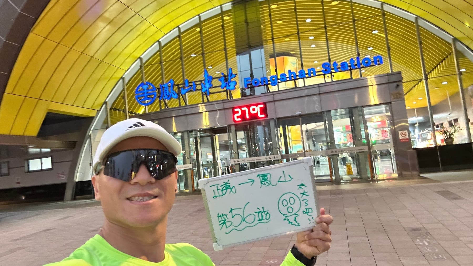 站主在鳳山站站牌前的走訪紀錄照,手持寫著「徒步環島 第 56 站 正義 → 鳳山」的白板