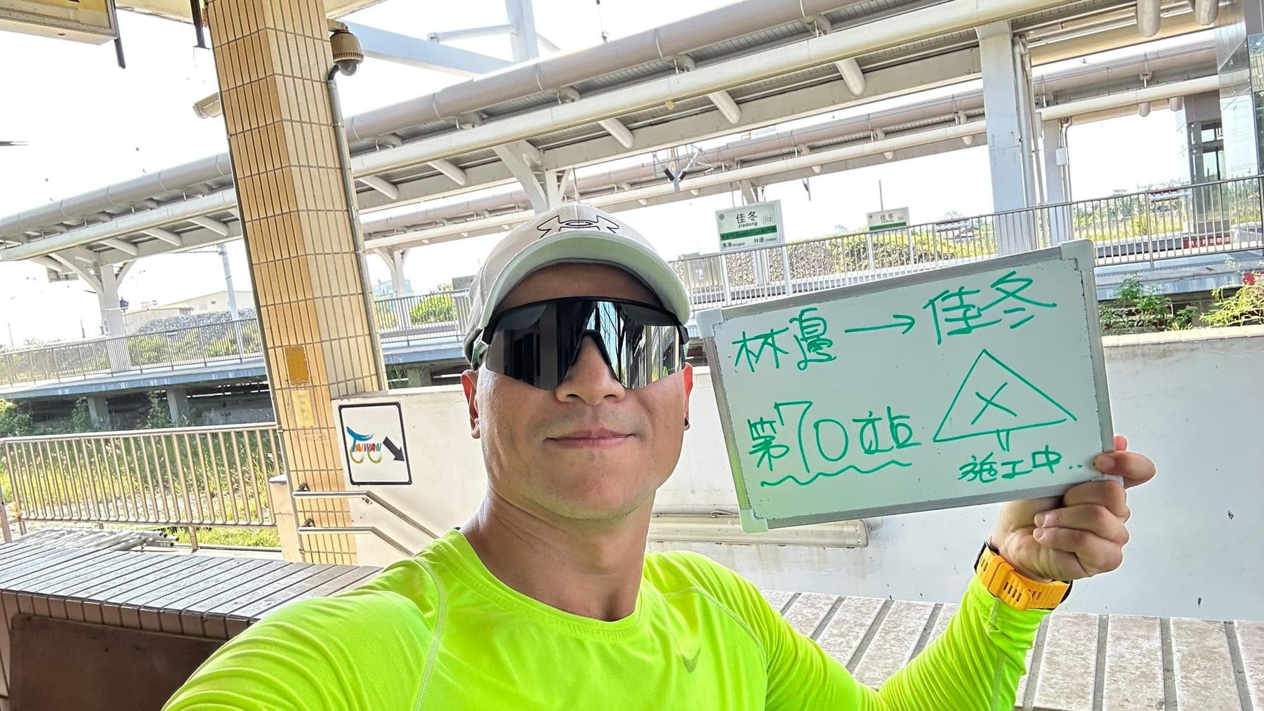 站主在佳冬站站牌前的走訪紀錄照,手持寫著「徒步環島 第 70 站 林邊 → 佳冬」的白板