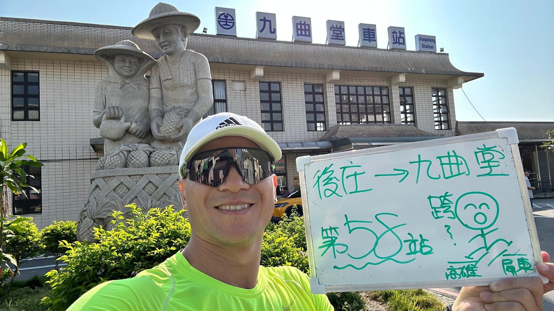 站主在九曲堂站站牌前的走訪紀錄照,手持寫著「徒步環島 第 58 站 後庄 → 九曲堂」的白板
