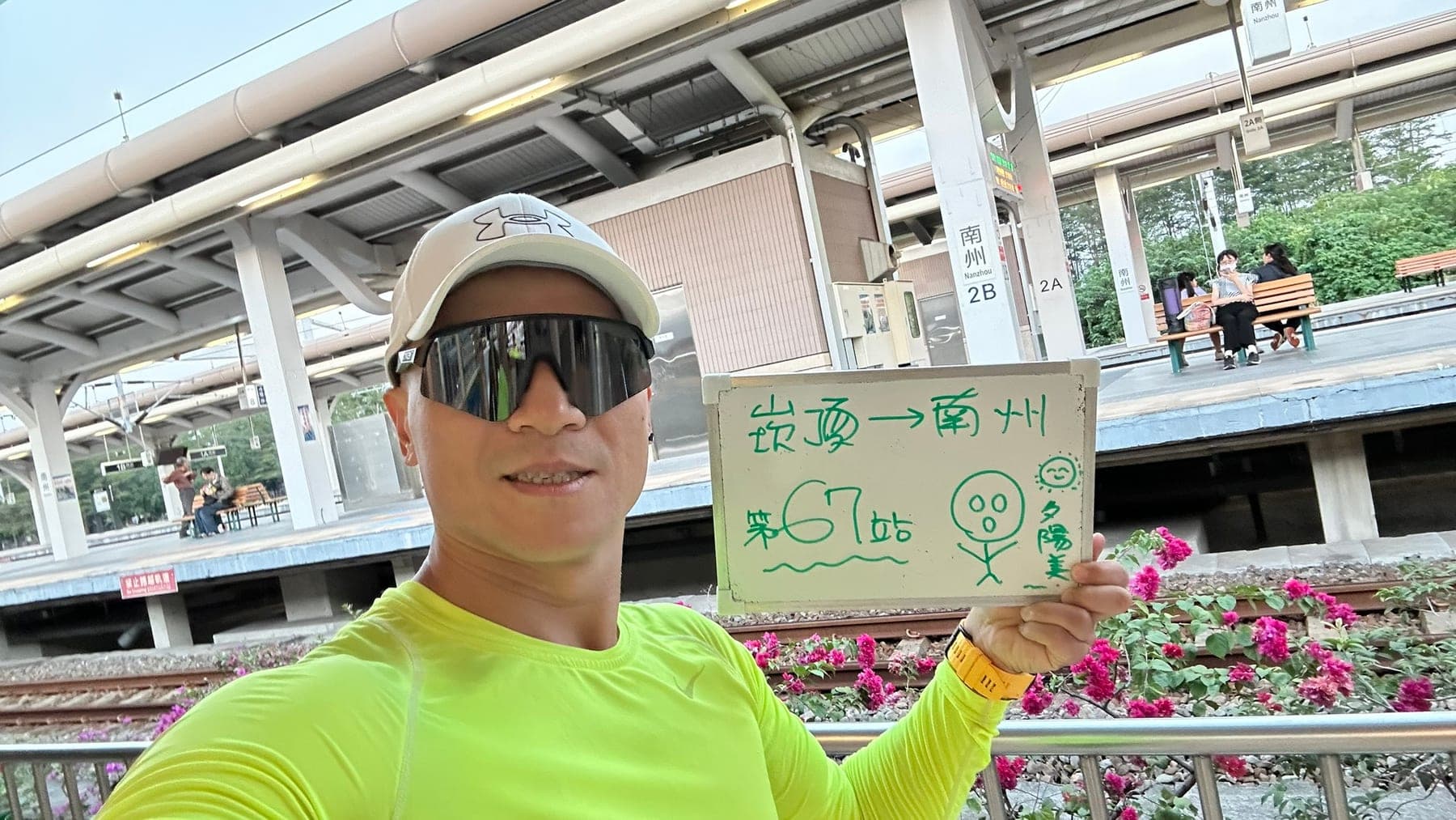 站主在南州站站牌前的走訪紀錄照,手持寫著「徒步環島 第 67 站 崁頂 → 南州」的白板