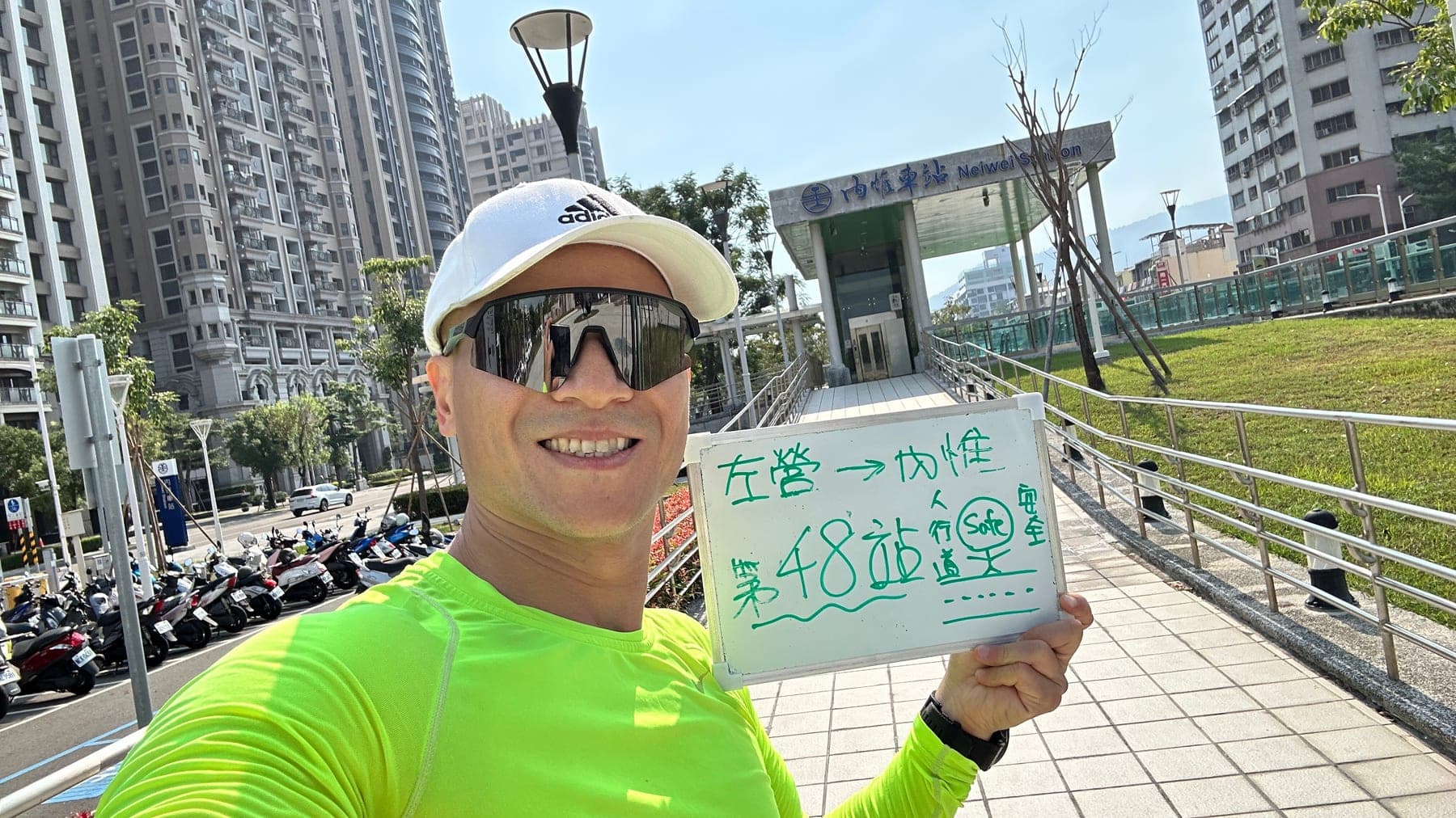 站主在內惟站站牌前的走訪紀錄照,手持寫著「徒步環島 第 48 站 左營 → 內惟」的白板