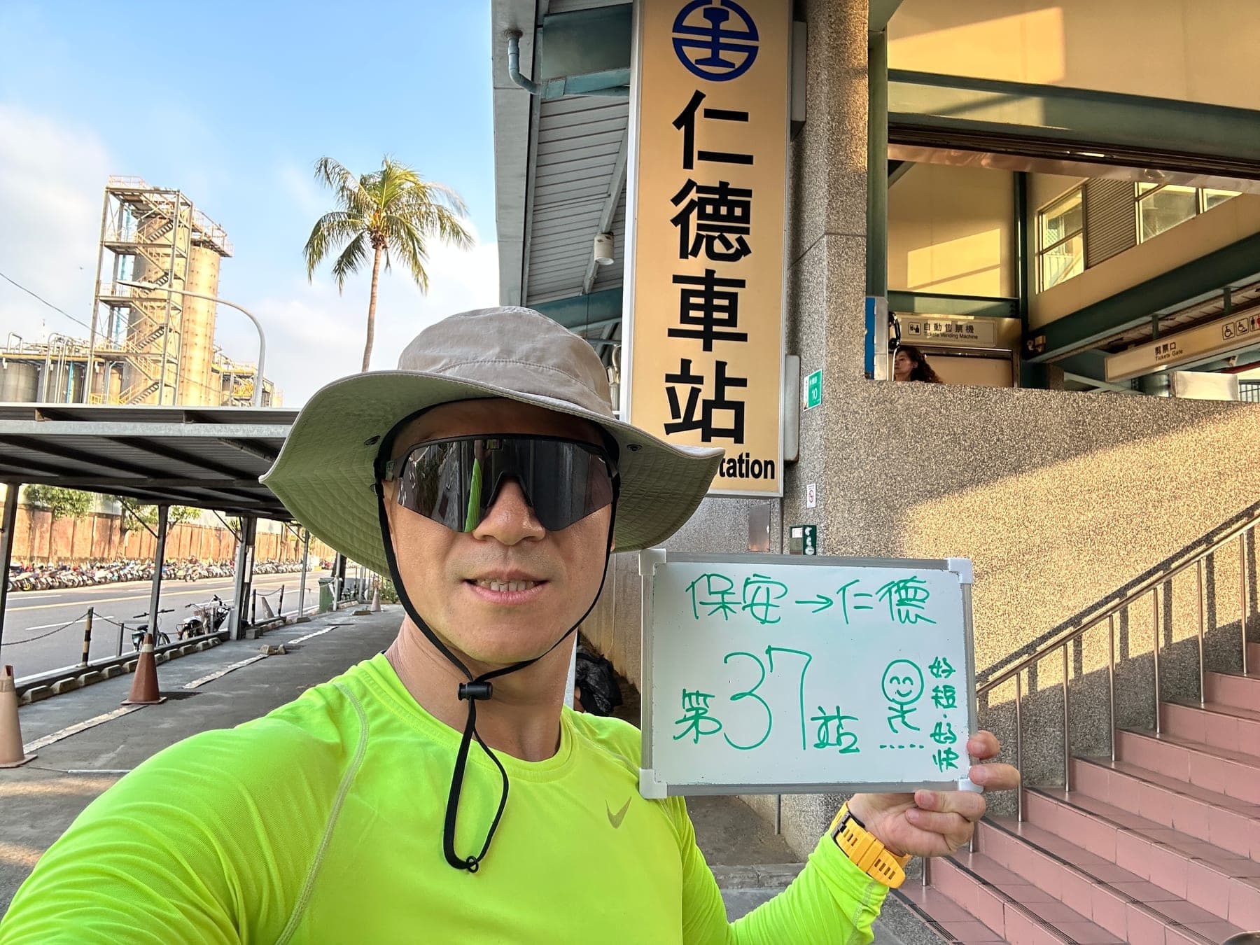 站主在仁德站站牌前的走訪紀錄照,手持寫著「徒步環島 第 37 站 保安 → 仁德」的白板