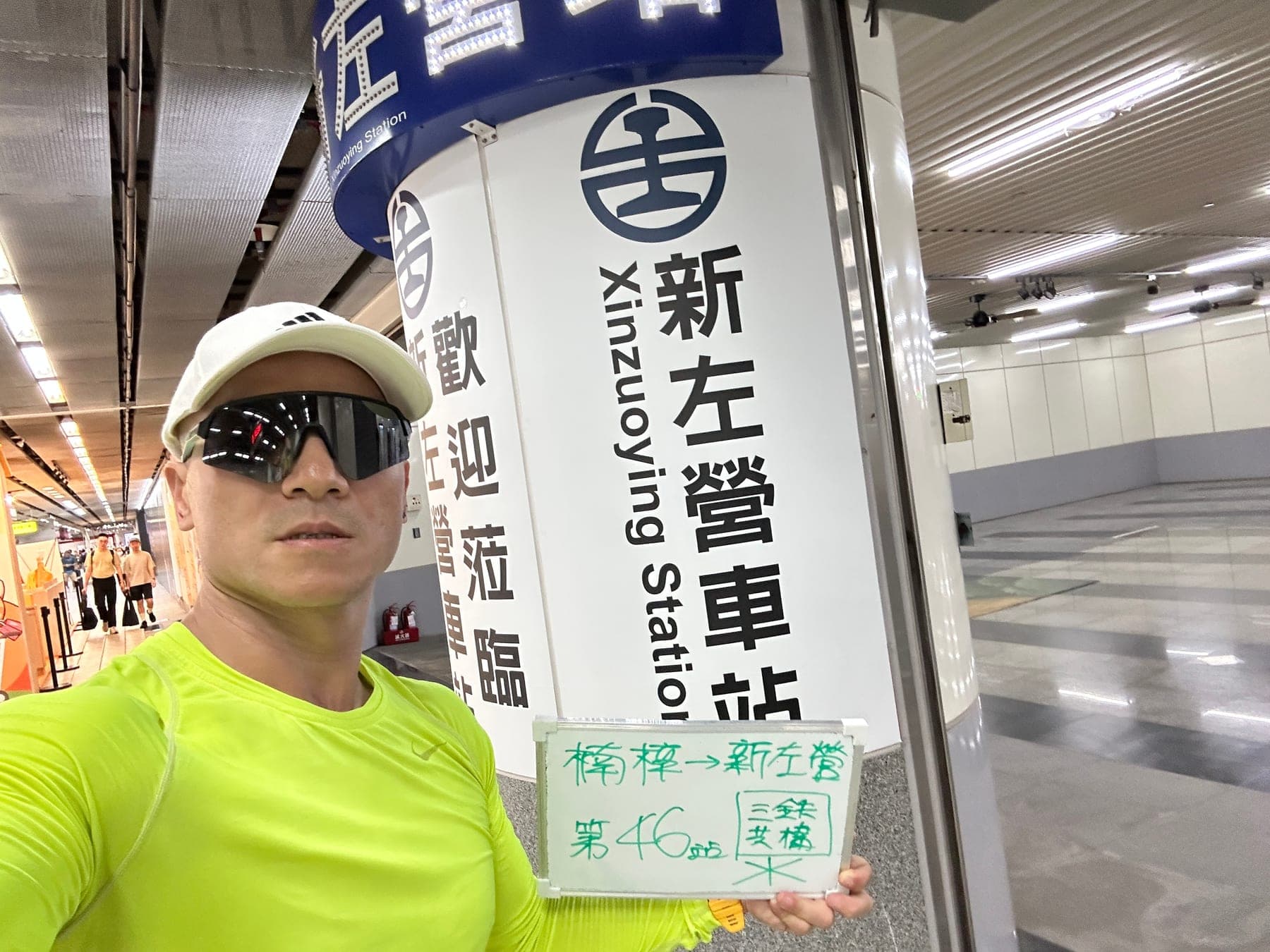 站主在新左營站站牌前的走訪紀錄照,手持寫著「徒步環島 第 46 站 楠梓 → 新左營」的白板